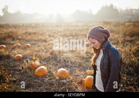 Young woman looking down thoughtfully in a pumpkin patch Stock Photo