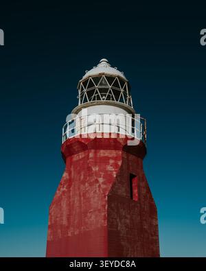 Vibrant red lighthouse tower against a clear blue sky in Newfoundland Stock Photo