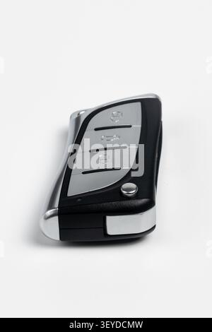 High-resolution studio photograph of a sleek modern car key fob shown from an angled perspective on a clean white background. This premium silver and Stock Photo