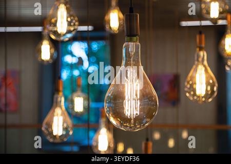 Group of decorative vintage Edison light bulbs glowing in a cozy interior. Modern industrial lighting decor. Stock Photo
