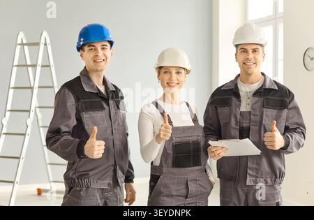 Confident construction workers team with helmets giving thumbs up on site Stock Photo
