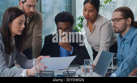 African American businessman leader with multiracial business team talking conversation analyze papers documents diversity five agents entrepreneurs Stock Photo