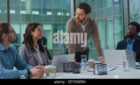 Caucasian man boss standing emotional talking explaining job tasks to multiracial business group multiethnic team women and men businesspeople Stock Photo