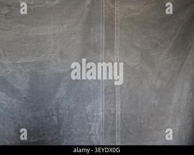 texture of thick, coarse-grained gray canvas. A double white seam runs vertically down the center, and faint creases, scuffs, and folds are visible Stock Photo