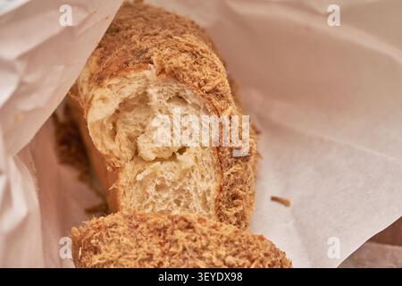 Fluffy Korean savory bread topped with shredded meat floss. This fresh bakery snack in paper packaging is ideal for food advertising and culinary mark Stock Photo