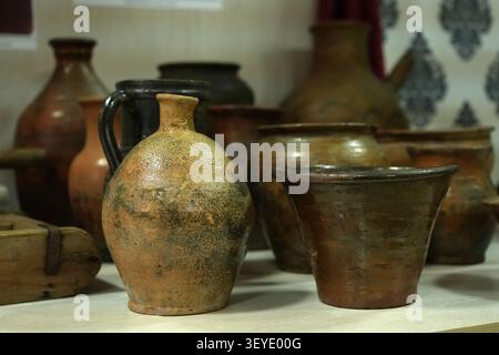 Rustic pottery, traditional craftsmanship, and antique decoration. Vintage clay jugs and ceramic pots on a wooden table. Stock Photo