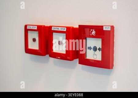 Manual fire alarm call points and emergency stop buttons installed on building wall. Fire safety equipment supports emergency response and building Stock Photo