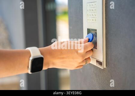 Person using contactless key fob on residential building access control system. Secure entry technology supports convenient and controlled property Stock Photo