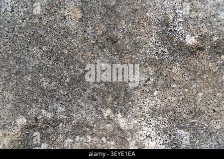 A close-up of a weathered concrete wall surface featuring rough texture, natural stains, and worn patterns Stock Photo