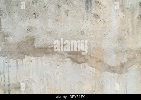 A weathered concrete wall with natural stains, rough textures, and aged surface patterns, creating an industrial grunge background. Stock Photo
