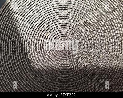 A close view of a circular woven texture showing uniform lines and patterns, set against a plain background that allows for additional text. Stock Photo