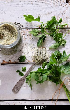Fresh parsley sprigs with seasoned salt in spoon on rustic white wooden background Stock Photo