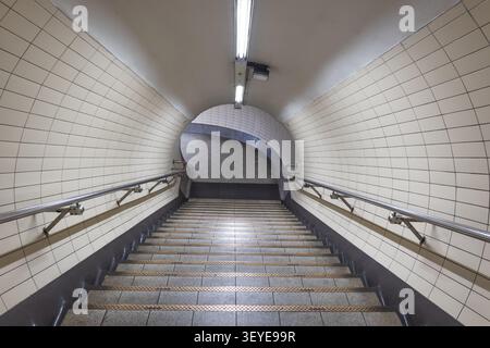Empty tiled pedestrian tunnel with stairs in a subway station Stock Photo