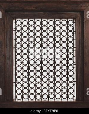 Geometric antique wooden frame with lattice grid window. Traditional architectural decorative lattice window with intricate carved details in classica Stock Photo