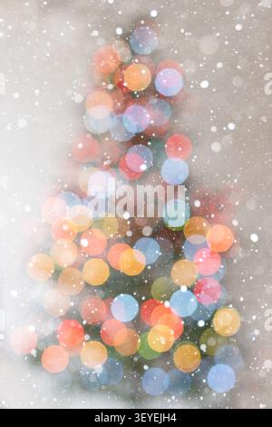 Elegant vertical Christmas background with soft warm bokeh lights and the subtle outline of a Christmas tree on a bright white background. Falling sno Stock Photo
