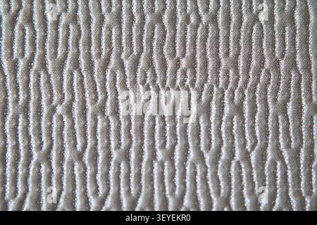 Quilted beige fabric texture with embossed wavy pattern close-up for background and design Stock Photo