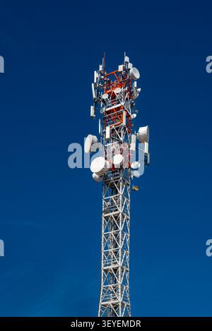 metal lattice telecommunication tower equipped with modern 5G cellular network antennas, transceivers, and microwave satellite dishes used for mobile Stock Photo