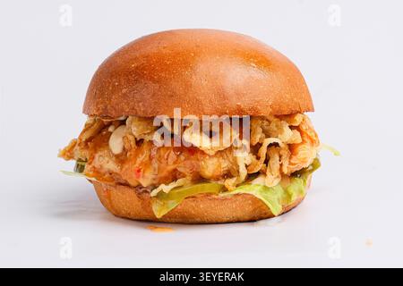 Crispy chicken burger with glazed bun, fried onions, lettuce and pickles on white background Stock Photo