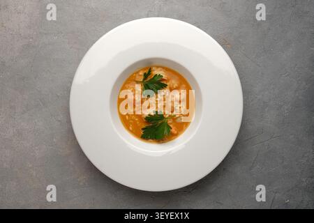White plate with shrimp risotto served in orange sauce on gray stone table Stock Photo