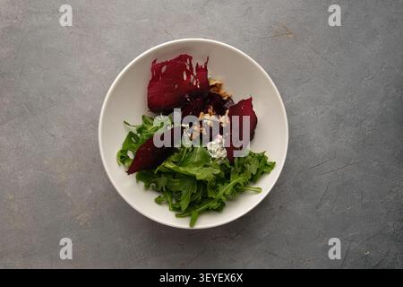 Gourmet beetroot salad with arugula, walnuts and creamy cheese on stone background Stock Photo