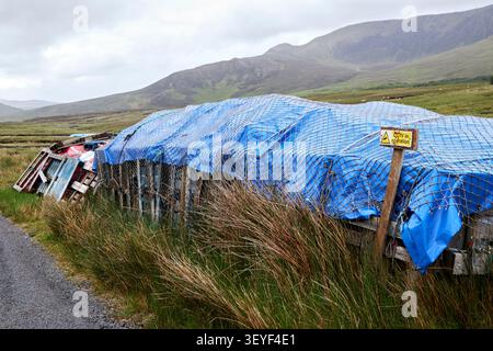cctv sign on stacked and covered freshly cut turf on the side of the road in a mountain bog area of malin more county donegal republic  of ireland Stock Photo