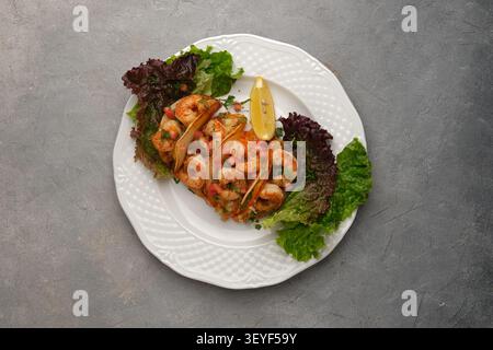Shrimp tacos with fresh lettuce and lemon garnish served on white plate Stock Photo