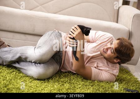 Young man playing with kitten at home Stock Photo