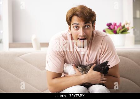 Young man playing with kitten at home Stock Photo