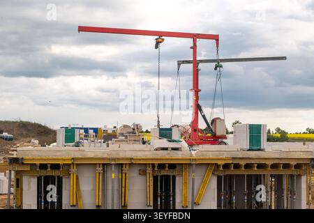 Heavy duty construction crane moving concrete blocks on top of a building under construction. House building concept. Stock Photo