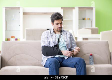 Young student man with hand injury sitting on the sofa Stock Photo