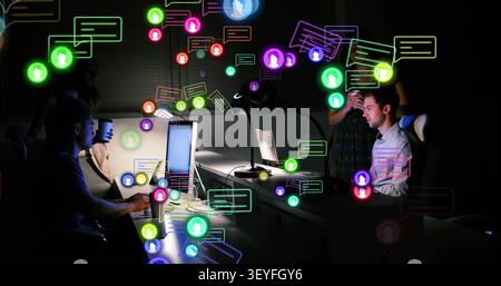 Office team working at monitors, woman checking phone, chat icons growing, showing message overload Stock Photo