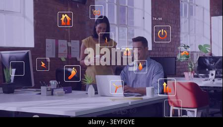 Man sitting at desk and woman walking in, initiating HUD showing energy metrics around laptop Stock Photo