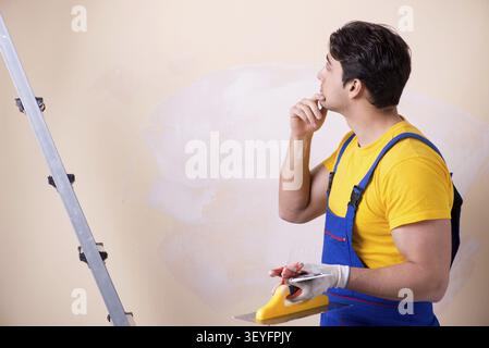 Young contractor employee applying plaster on wall Stock Photo