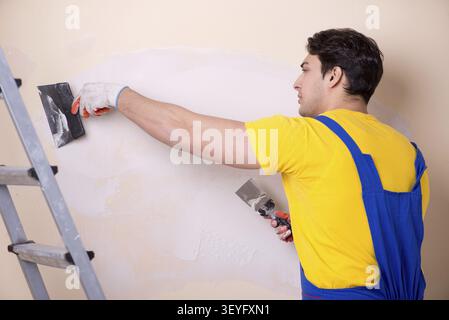 Young contractor employee applying plaster on wall Stock Photo