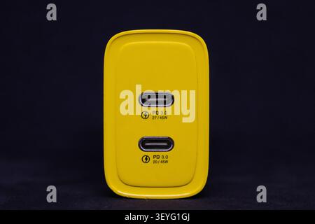 A charging device shows its two USB ports on a dark background. The device is yellow and designed for quick charging. It displays power specifications Stock Photo