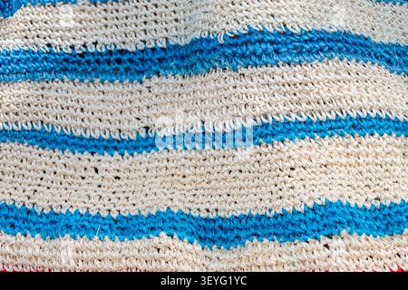 Handwoven natural fiber fabric presenting a wavy blue and off-white striped design, creating a textured background highlighting traditional craftsmans Stock Photo