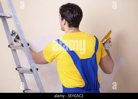 Young contractor employee applying plaster on wall Stock Photo