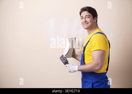 Young contractor employee applying plaster on wall Stock Photo