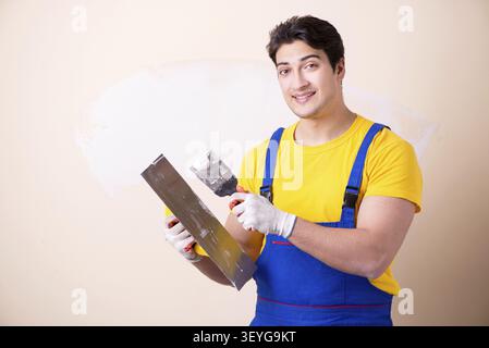 Young contractor employee applying plaster on wall Stock Photo