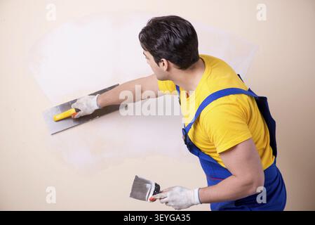 Young contractor employee applying plaster on wall Stock Photo