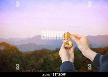 HIker holding compass in hand against mountains, closeup Stock Photo