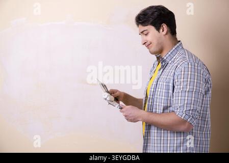 Young man applying plaster on wall at home Stock Photo