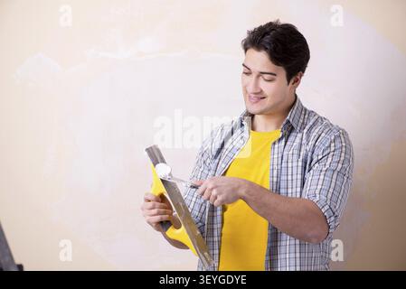 Young man applying plaster on wall at home Stock Photo