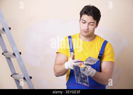 Young contractor employee applying plaster on wall Stock Photo