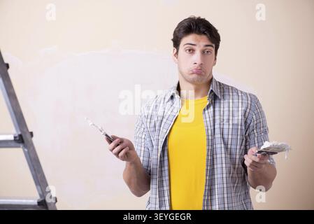Young man applying plaster on wall at home Stock Photo