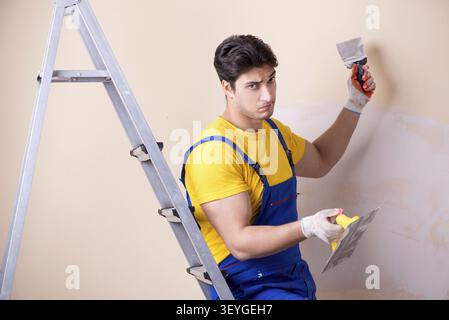 Young contractor employee applying plaster on wall Stock Photo