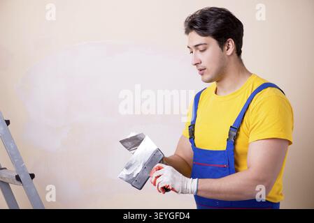 Young contractor employee applying plaster on wall Stock Photo