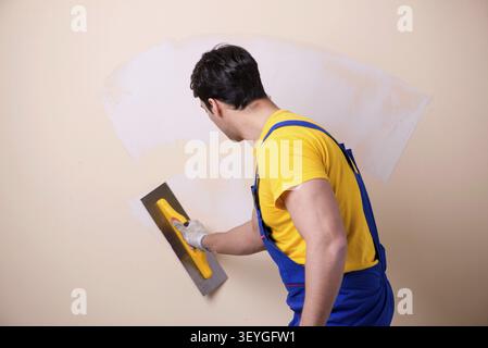Young contractor employee applying plaster on wall Stock Photo