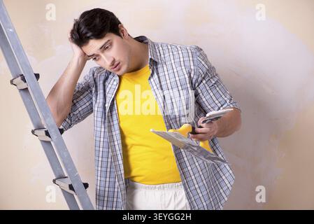 Young man applying plaster on wall at home Stock Photo