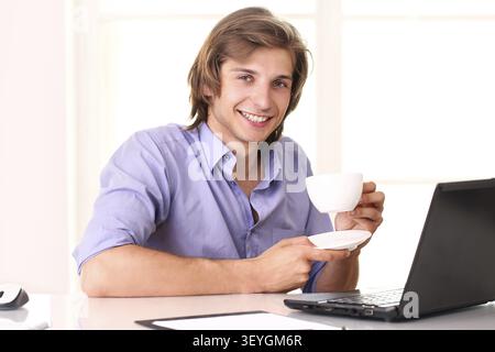 Young businessman taking a break with cup of coffee in his office Stock Photo